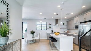 Una cucina moderna con isola centrale, mobili bianchi ed elettrodomestici in acciaio inossidabile.
