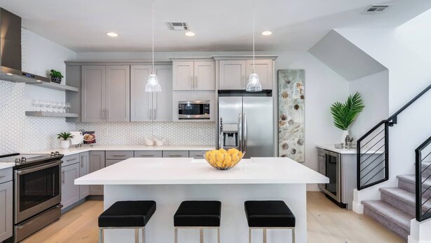 Una cucina moderna con isola centrale, elettrodomestici in acciaio inossidabile e illuminazione a sospensione.