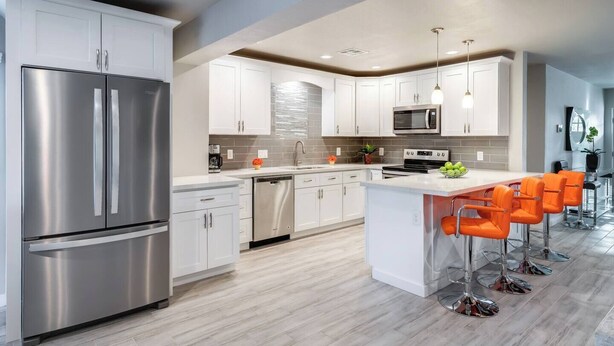 A modern kitchen with stainless steel appliances, white cabinetry, and a central island with bar stools. - Stylish Scottsdale Home & Pool Table (Phoenix)