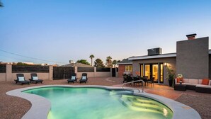 A modern outdoor pool area with lounge chairs and a dining set. - Stylish Scottsdale Home & Pool Table (Phoenix)