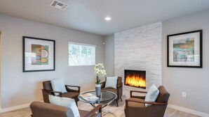 A modern living room with a fireplace, comfortable seating, and artwork on the walls. - Stylish Scottsdale Home & Pool Table (Phoenix)