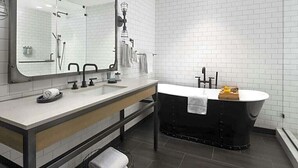 A modern bathroom with a large mirror, two sinks, a black bathtub, and a towel rack. - Enjoy all San Francisco has to offer for Super Bowl Weekend! (San Francisco)