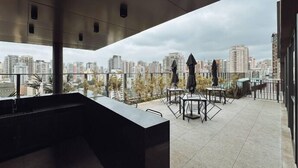 Una terraza en la azotea con vistas a la ciudad, mobiliario exterior y un diseño arquitectónico moderno.