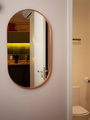 Un baño con inodoro, espejo y lavamanos con toallero.