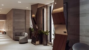 A modern interior with a sofa, potted plants, and geometric wall designs. - Soma Perdizes 804 (São Paulo)