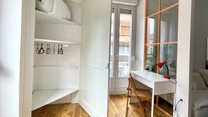 Une pièce comprenant un bureau blanc, une chaise et une étagère sur laquelle sont accrochés divers objets.