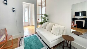 Un salon moderne avec un canapé, une table basse, un téléviseur et une plante.