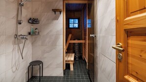 A bathroom with a shower, a toilet, and a wooden door. - Alpine Fox by Aavalevi (Levi)