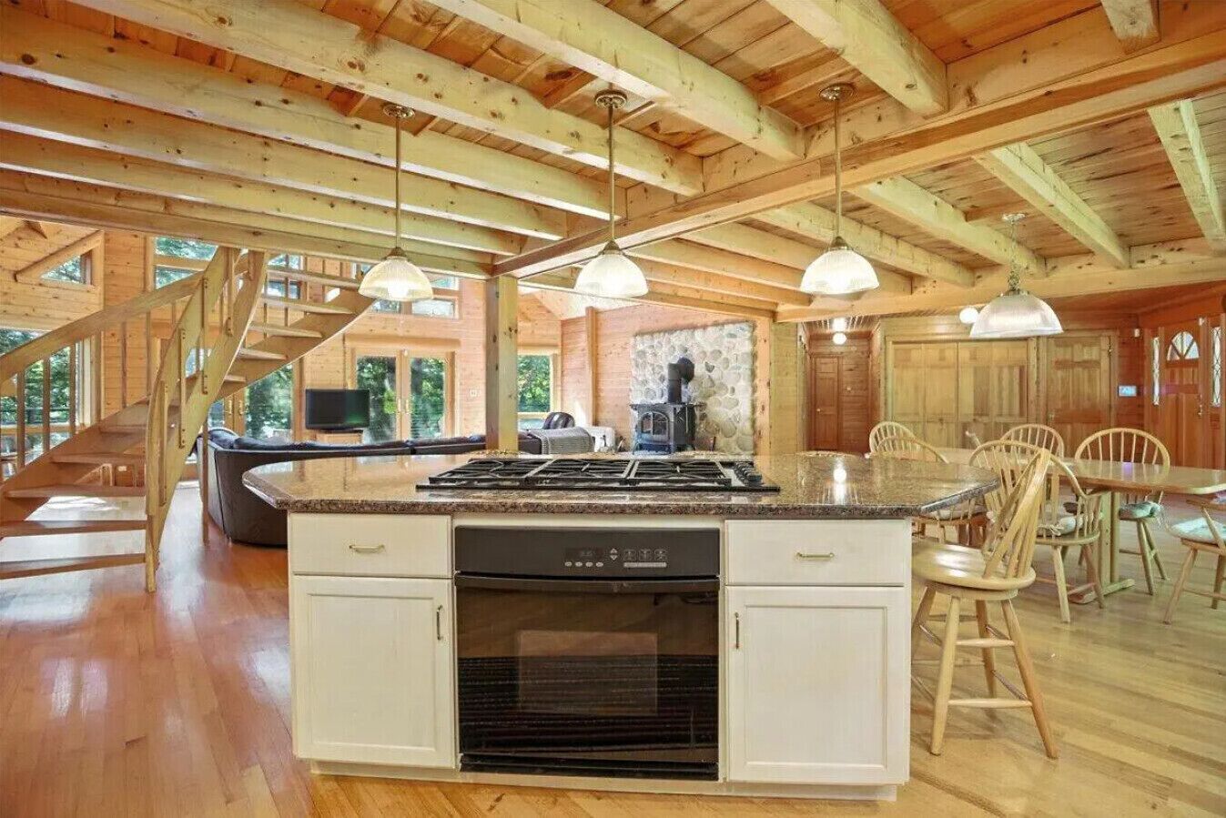 Una cocina amplia con una isla central, vigas de techo de madera e iluminación colgante.