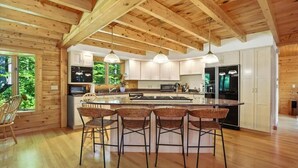 Una cocina amplia con una isla grande, vigas de madera en el techo y taburetes de bar.