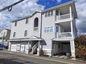 Ein zweistöckiges Wohnhaus mit Veranda, Treppe und Garage.