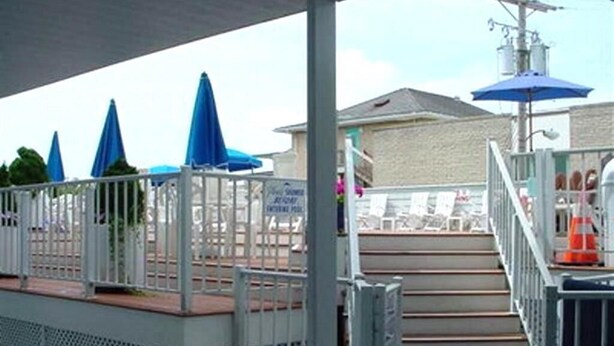 Un espacio al aire libre techado con escaleras que conducen a una zona de piscina, una valla y un poste de servicios.