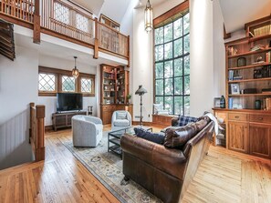 A spacious living room with a large window, a wooden staircase, and a cozy seating area. - Your Perfect Shore Getaway Awaits (Ocean City)