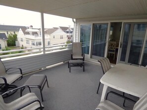 A covered outdoor area with a table and chairs, a small table, and a chair. - Steps from the Sand, Ultimate Coastal Retreat (Ocean City)
