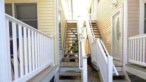 Un escalier étroit avec des rampes blanches mène à une porte, flanquée de murs recouverts de lambris beiges.