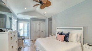 Un dormitorio con una cama grande, un ventilador de techo, un aparador y vistas al exterior.
