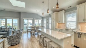 Una cocina amplia con una isla grande, taburetes de bar e iluminación colgante.