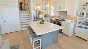 A modern kitchen with white cabinetry, a central island, and pendant lighting. - Perfect Getaway Near Ocean City’s Famous Gold Coast (Ocean City)