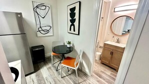 A compact kitchen with a refrigerator, a dining table with chairs, and a small potted plant. - Jr. Suite ATLAS- The Agustin Guesthouse for Men, a beautiful & sexy resort oasis (Fort Lauderdale)