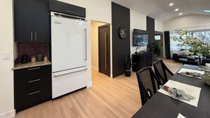 Une cuisine moderne avec un réfrigérateur blanc, des meubles de couleur sombre et un plan de travail en bois.