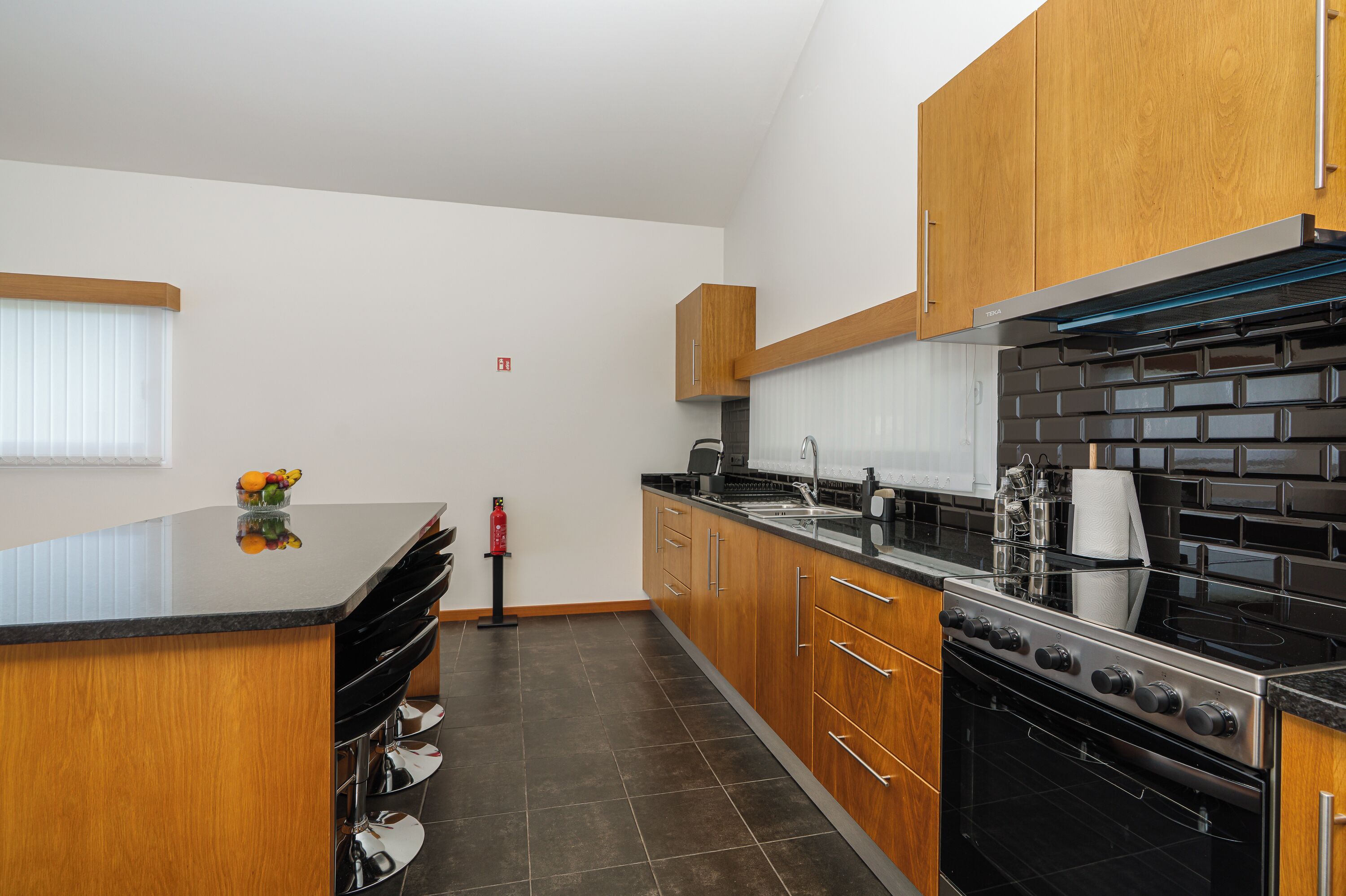 Una cocina moderna con armarios de madera, estufa negra y encimera de granito.