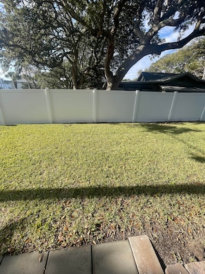 A well-maintained lawn with a white fence, a large tree, and a house in the background. - 5 O'Clock Somewhere (North Myrtle Beach)