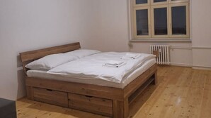 Un dormitorio con una cama de madera, una ventana y un radiador.