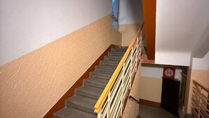 Una escalera con barandilla amarilla que lleva a un rellano con un letrero de salida de emergencia roja.