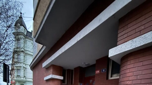 Un edificio de ladrillo rojo, con una puerta roja y un pequeño tramo de escalones que conducen a la entrada.