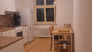 Cocina compacta con zona de comedor, que incluye estufa, refrigerador y ventana con persianas.