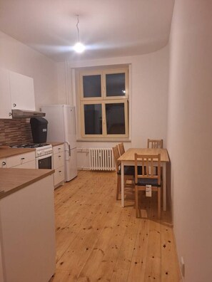 Een koelkast, een oven, een kookplaat, kookgerei, borden en bestek