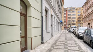 Una estrecha calle adoquinada bordeada por vehículos estacionados y edificios.
