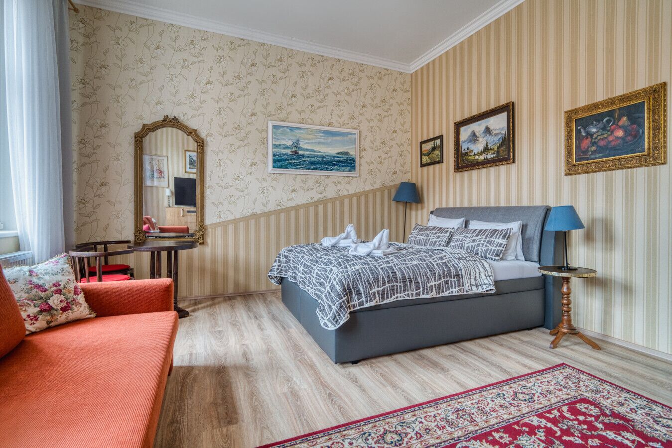 A bedroom with a bed, a desk, a chair, a sofa, and a rug.