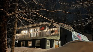 Un edificio di due piani con un balcone, bandiere americane e luci a stringa.