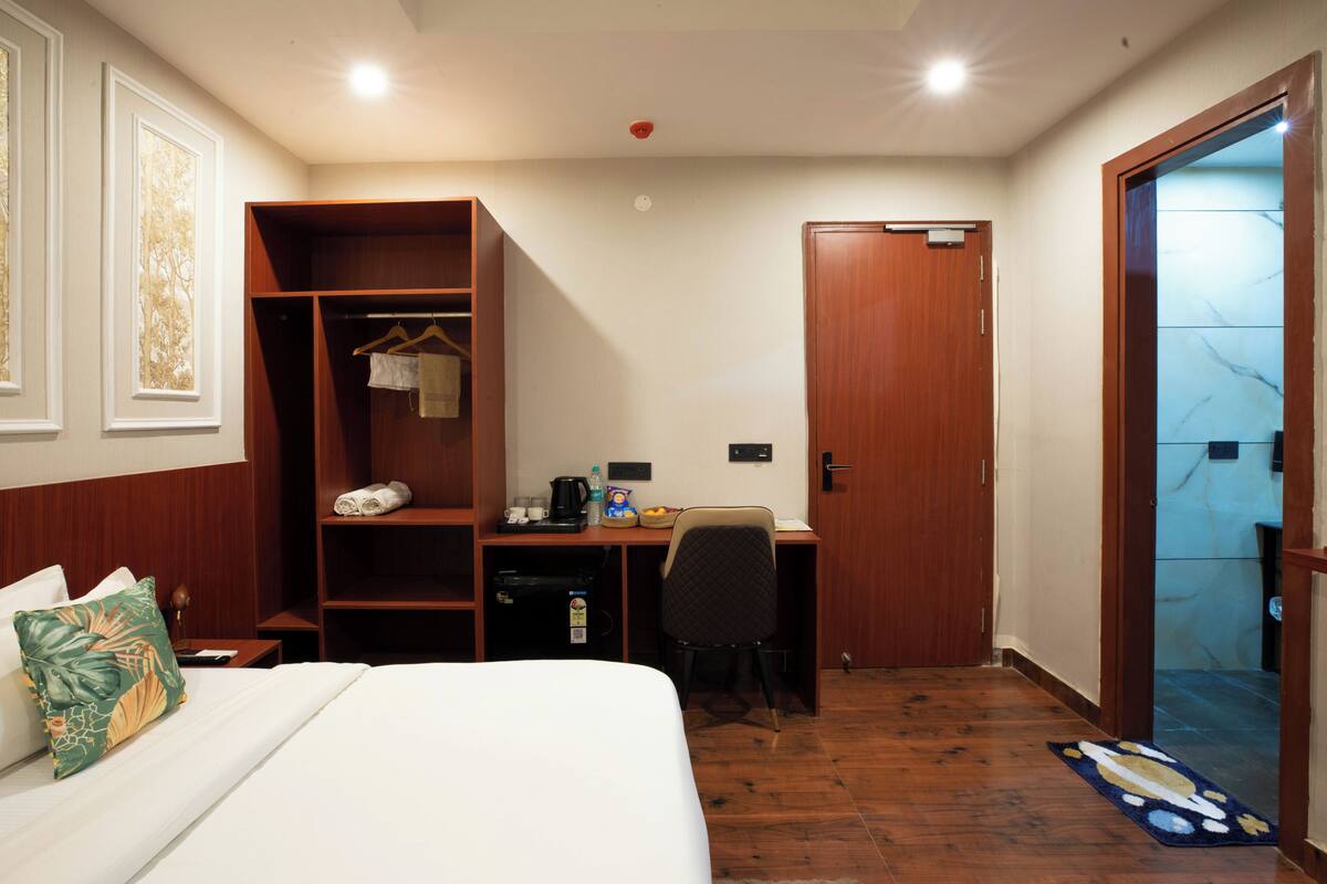 A hotel room with a bed, a desk, a wardrobe, and a door leading to a bathroom.