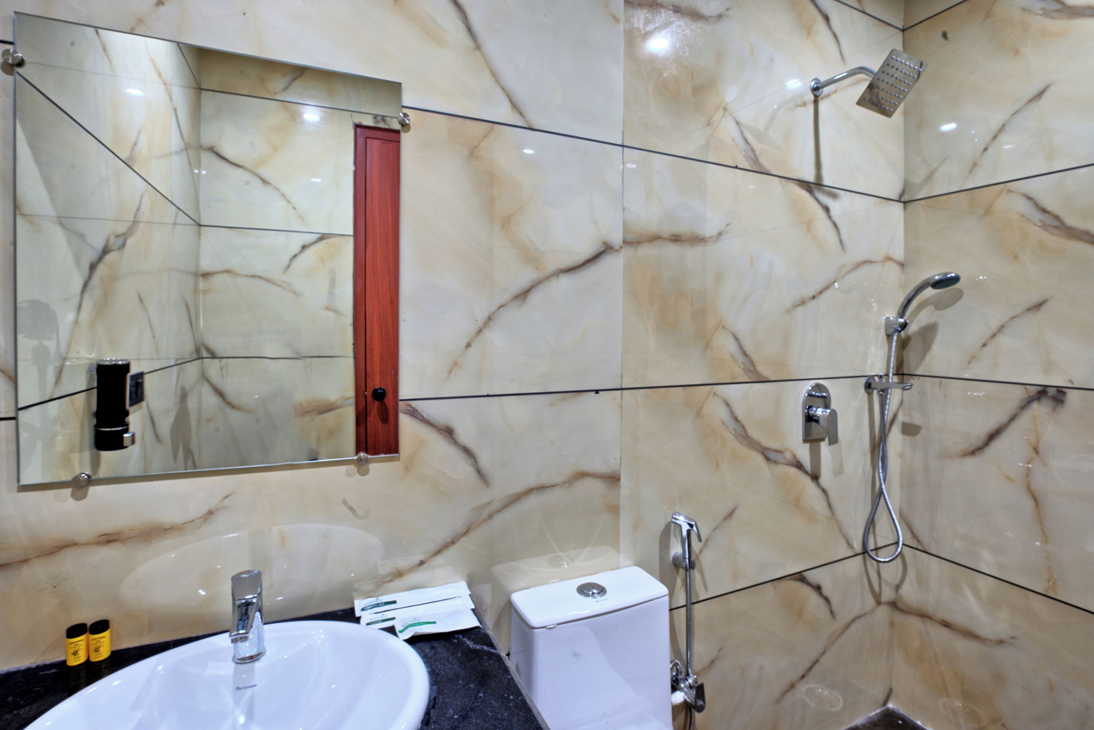 Un baño con pared de mármol, un lavabo, un inodoro y una ducha.