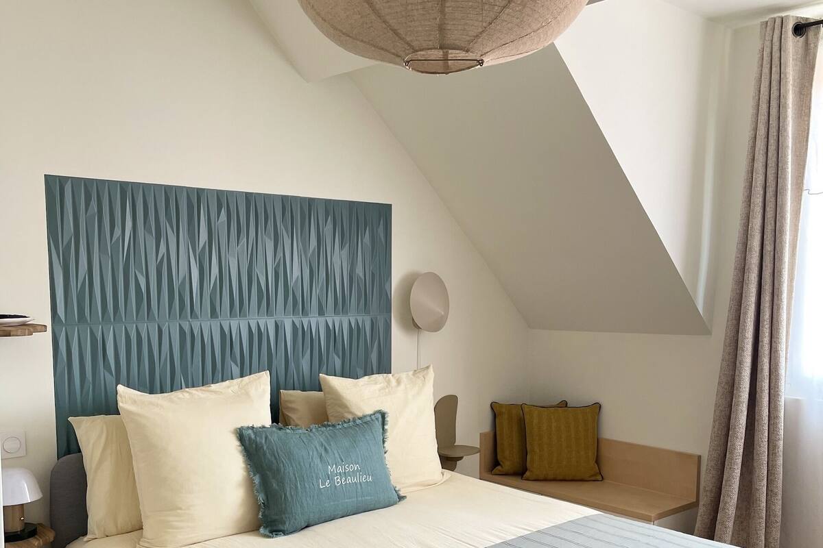 A bedroom with a large bed, a blue headboard, and a hanging light fixture.