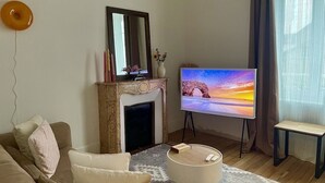 A living room with a fireplace, a television, a sofa, and a small table. - Maison Le Beaulieu (Vichy)