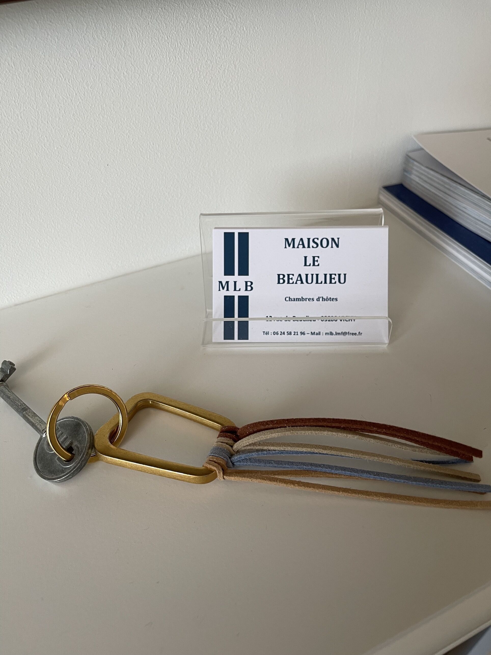 Naambordje met 'MAISON LE BEAULIEU' en een sleutel met sleutelhanger.