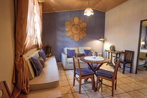 Una sala acogedora con un sofá, sillas, una mesa y un elemento decorativo en la pared.