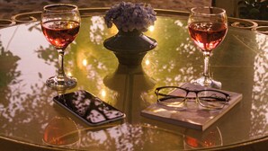 Une table en verre avec deux verres à vin, un téléphone intelligent et une paire de lunettes.