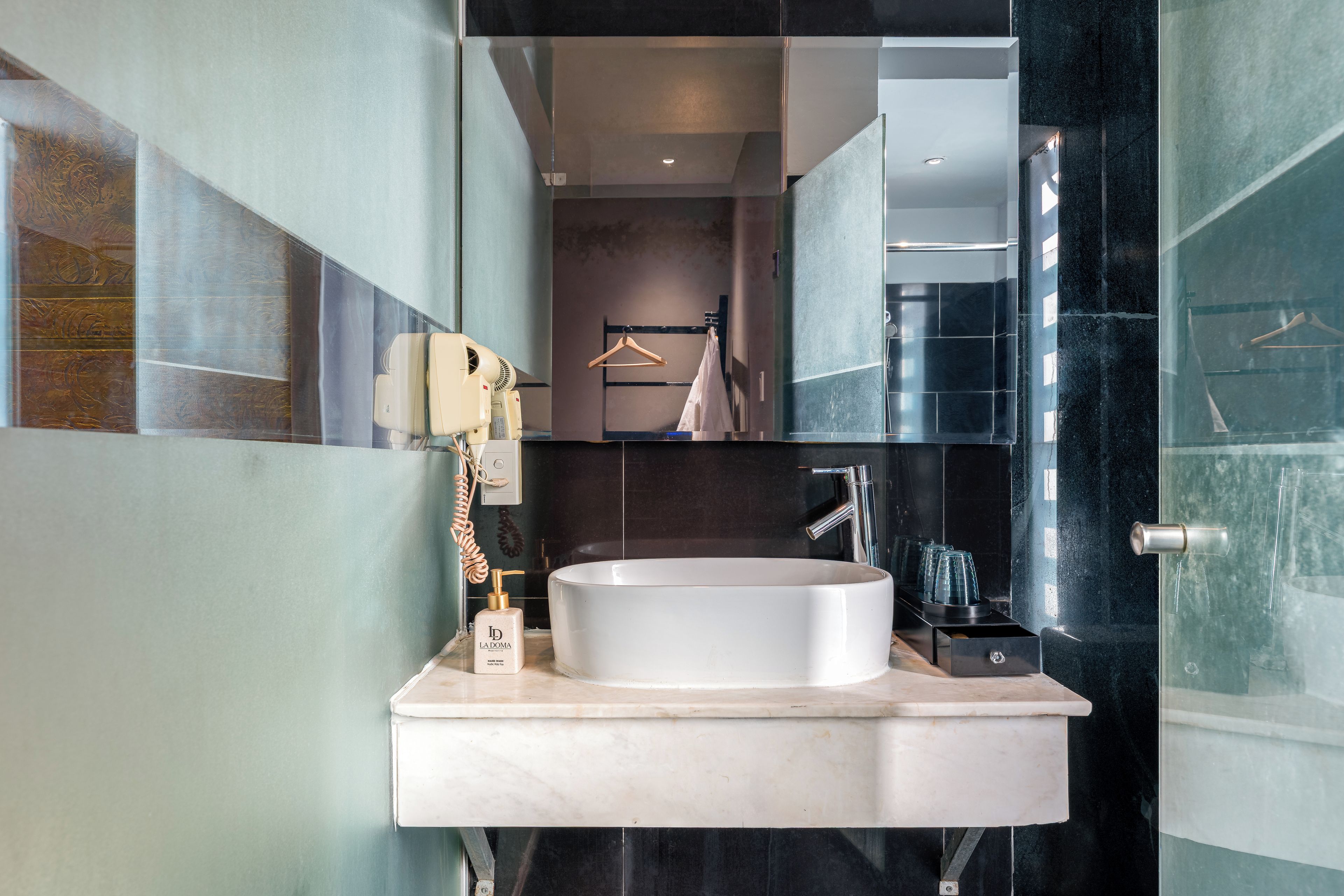 A modern bathroom with a large mirror, a round sink, and a towel rack.