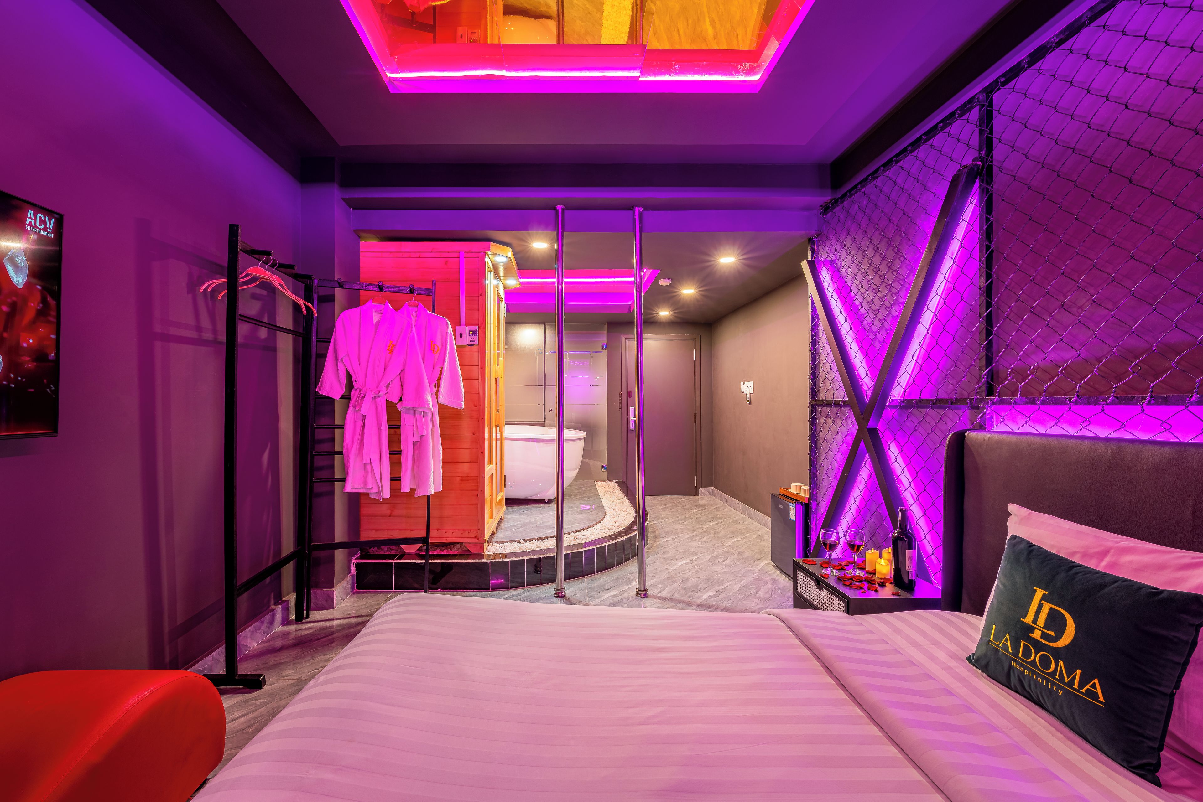 A modern hotel room with a bed, a seating area, and a bathroom visible through a glass door.