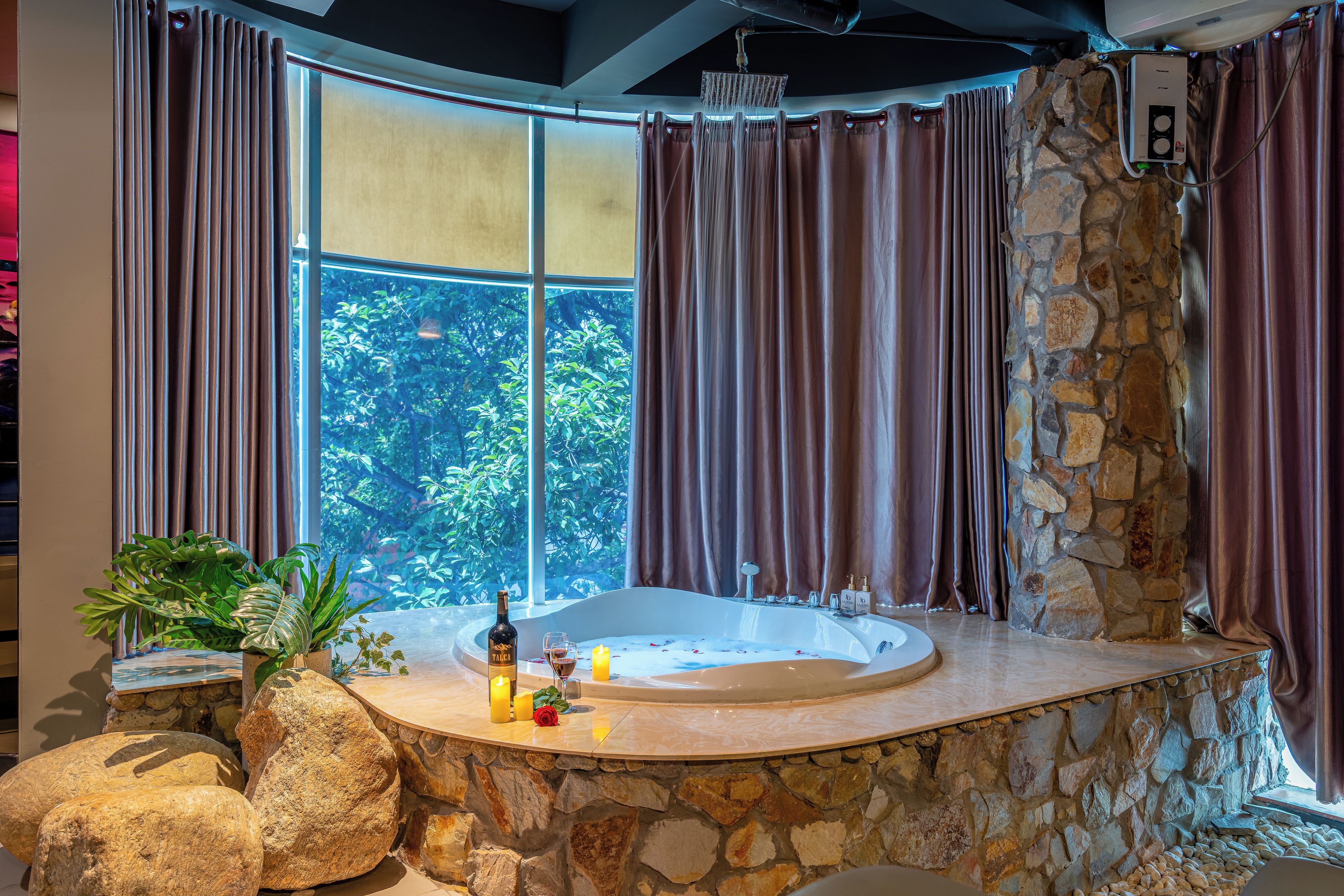 Ein Badezimmer mit Steinwand, einer Badewanne und einem Fenster mit Vorhängen.