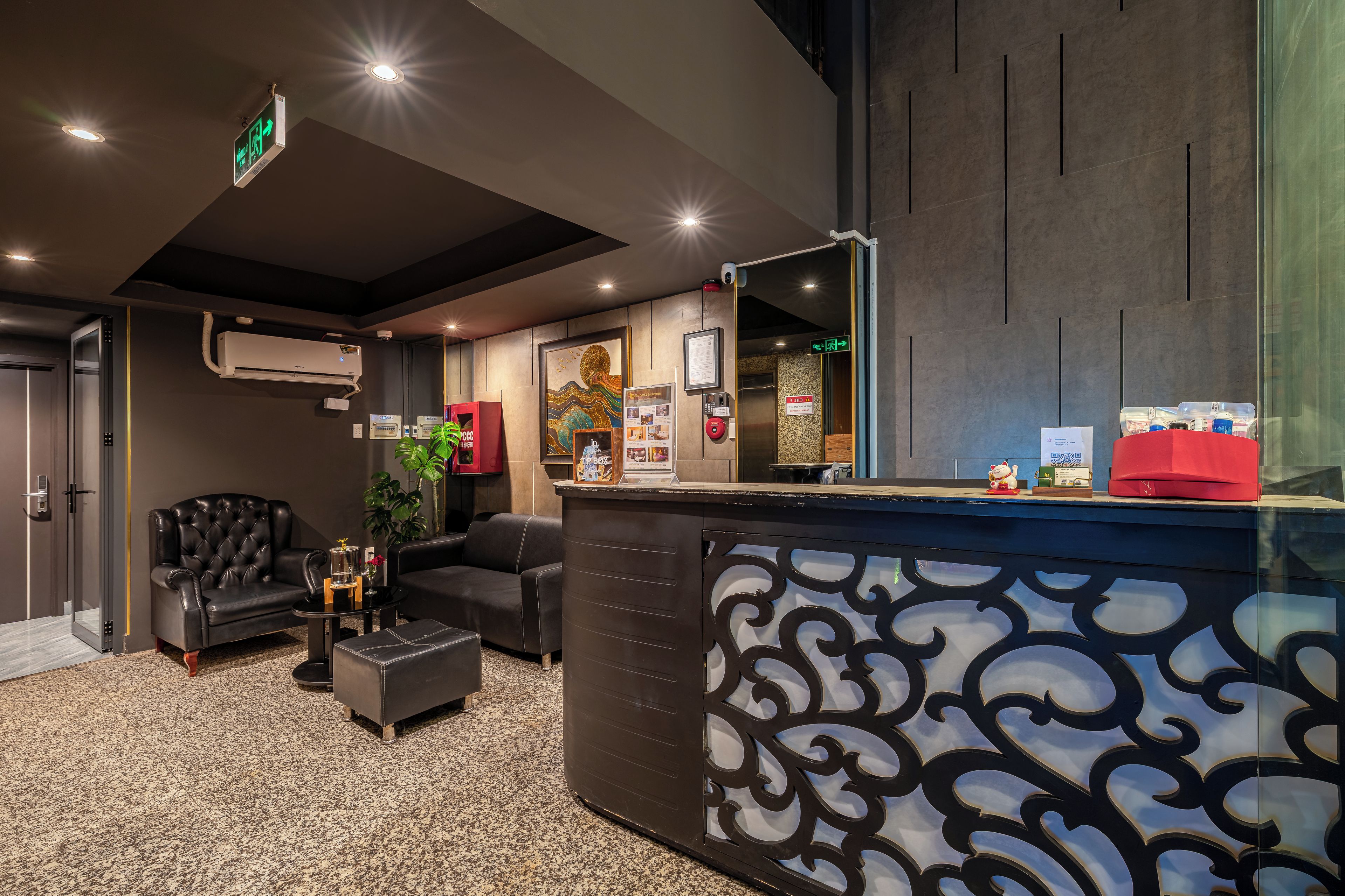 A modern reception area with a black and white patterned counter, leather seating, and an air conditioning unit.