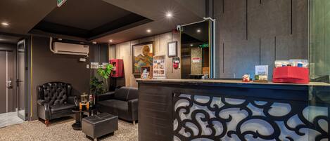 A modern reception area with a black and white patterned counter, leather seating, and an air conditioning unit.