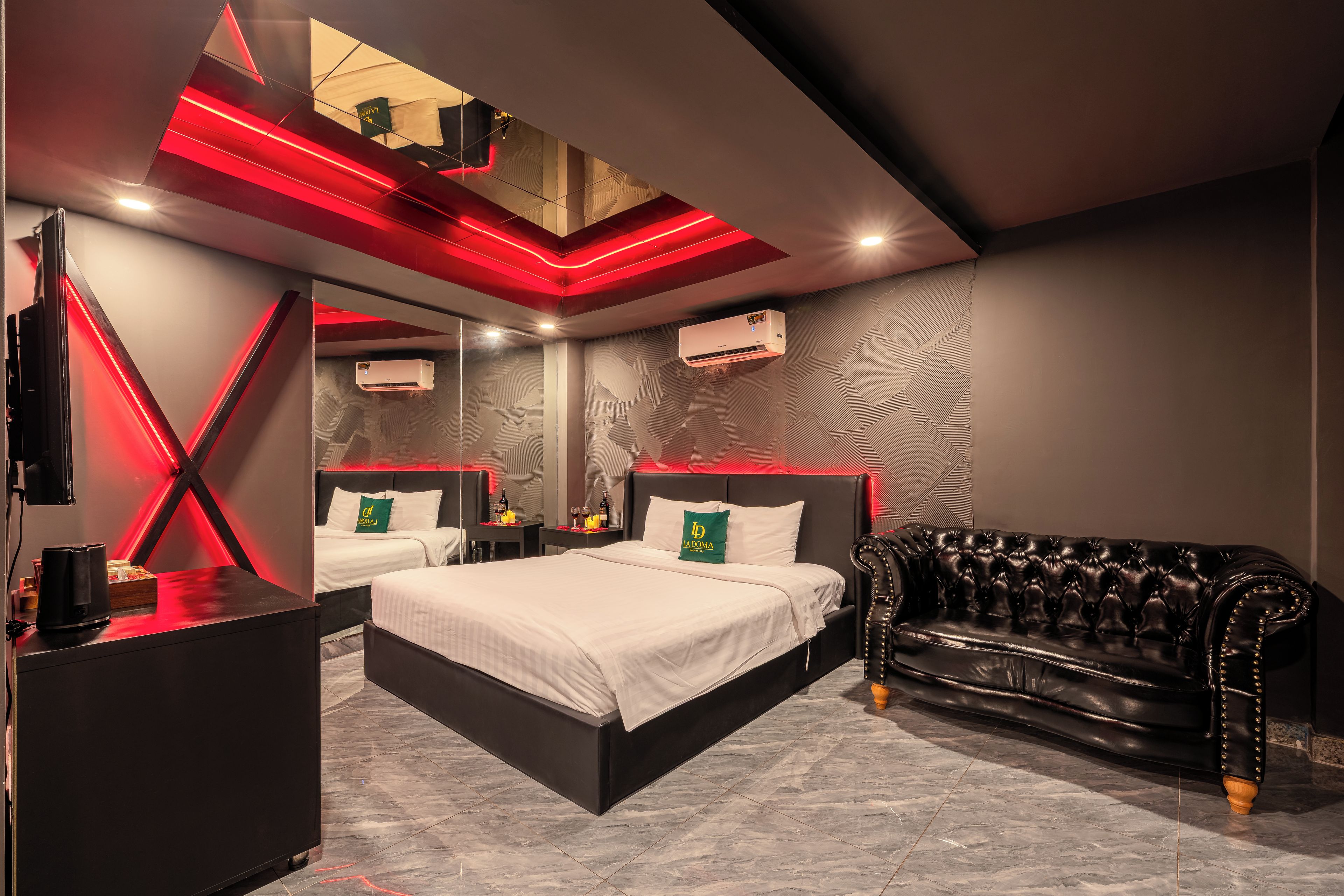 Une chambre d’hôtel moderne avec un grand lit, un canapé en cuir et un minibar.