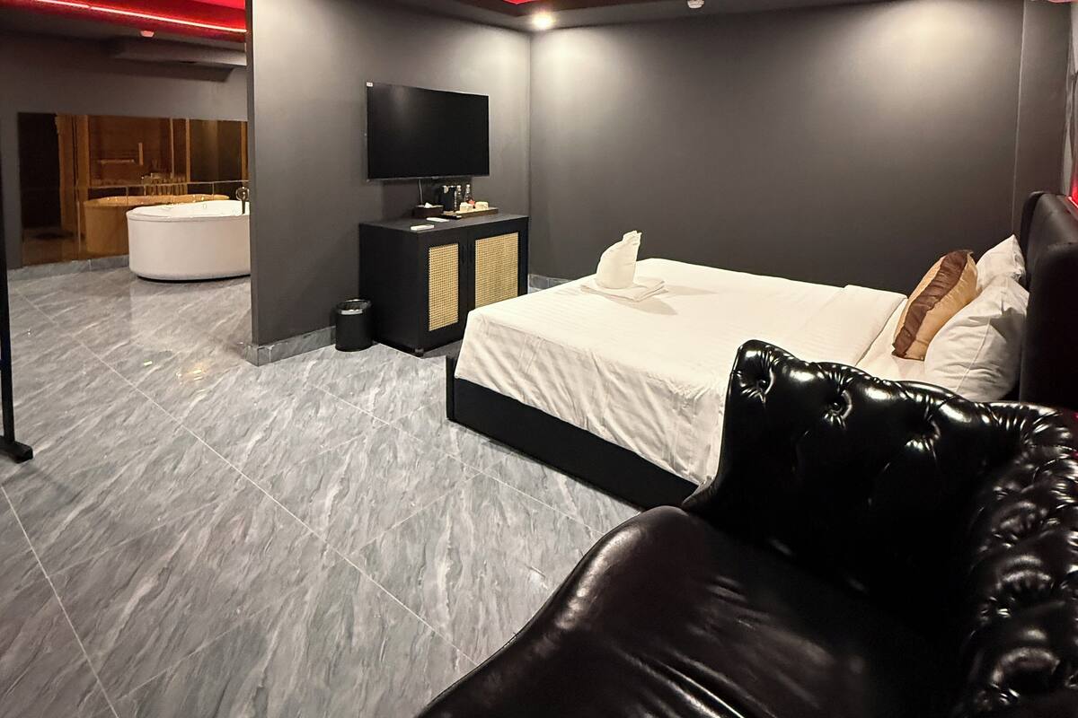 Ein modernes Schlafzimmer mit einem großen Bett, einem Fernseher und einer Sitzecke.