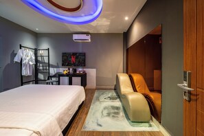 A modern bedroom with a bed, a seating area, a TV, and an air conditioning unit. - La Doma en Amour Hotel (Ho Chi Minh City)