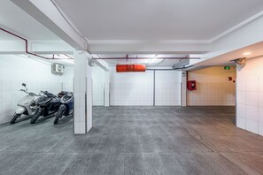 A clean, well-lit indoor space with tiled floors, a ceiling with visible pipes and a fan, and a red emergency exit sign. - La Doma en Amour Hotel (Ho Chi Minh City)